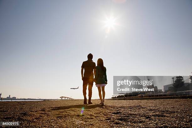 couple holding hands and watching aircraft land - ouder-volwassenen-koppel stockfoto's en -beelden
