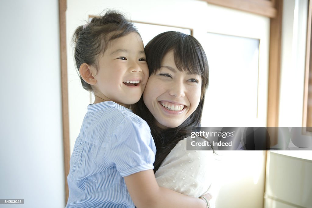 Mother holding daughter, smiling, portrait