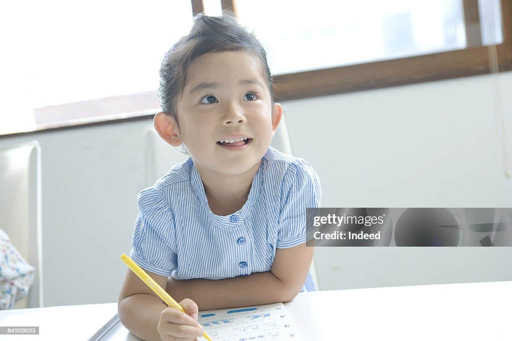 Girl doing her homework and looking away, smiling