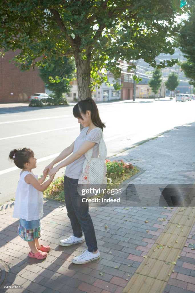 Mother and daughter holding hands on street