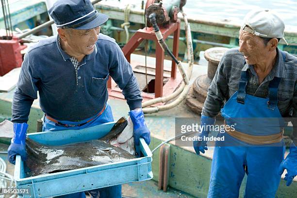 japanese fishermen carrying crate of flounder - carrying box stock pictures, royalty-free photos & images