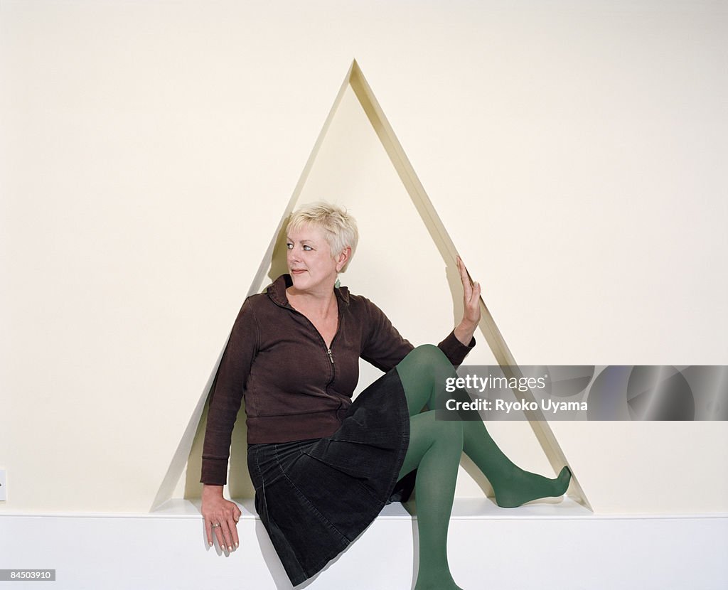 A woman sitting down between walls