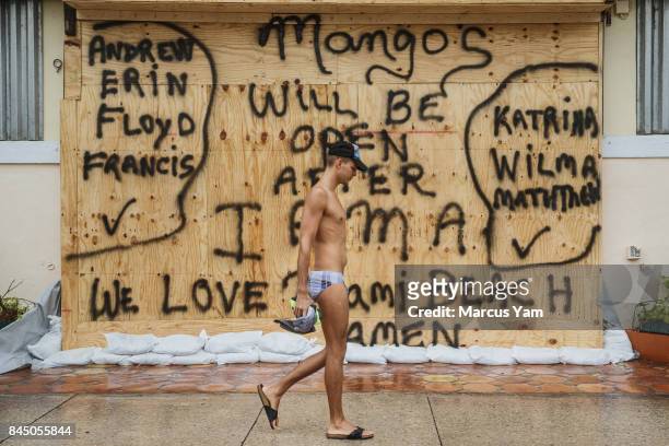 An unidentified man, who declined to give his name, walks past the boarded up Mango, a nightclub on Ocean Drive in Miami Beach, Fla., on Sept. 9,...