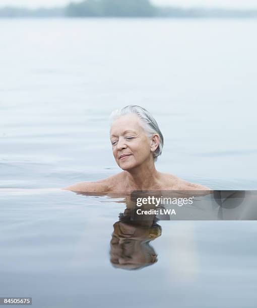 naked woman relaxing in lake - einzelne frau über 40 stock-fotos und bilder