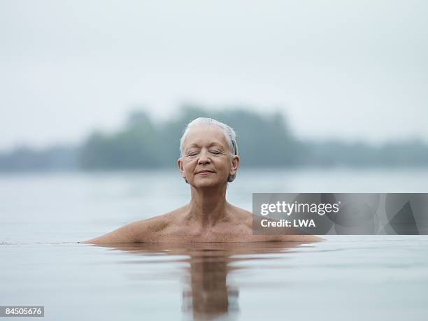 naked woman sitting in lake, eyes closed - locs hairstyle stockfoto's en -beelden