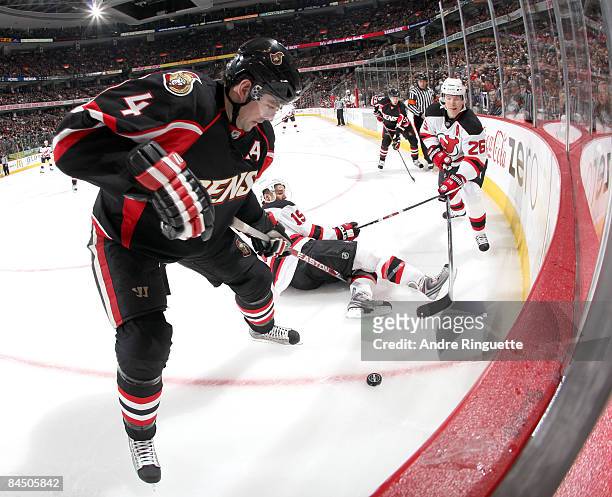 Chris Phillips of the Ottawa Senators digs for a loose puck in the corner against Patrik Elias of the New Jersey Devils at Scotiabank Place on...