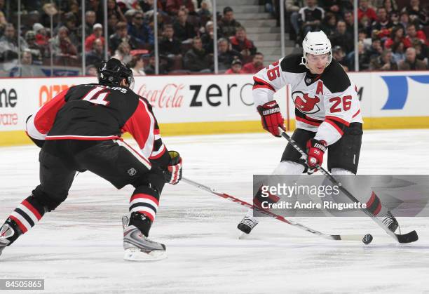 Patrik Elias of the New Jersey Devils stickhandles the puck against the poke check of Chris Phillips of the Ottawa Senators at Scotiabank Place on...