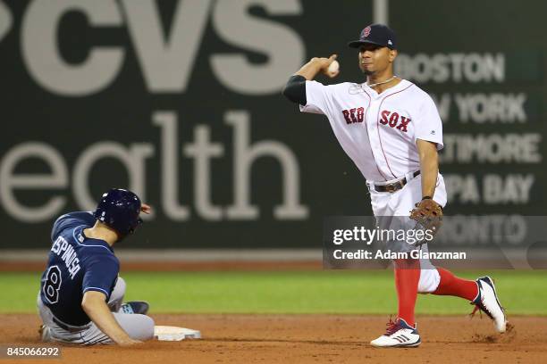 Xander Bogaerts of the Boston Red Sox turns a double play over the slide of Danny Espinosa of the Tampa Bay Rays in the seventh inning at Fenway Park...