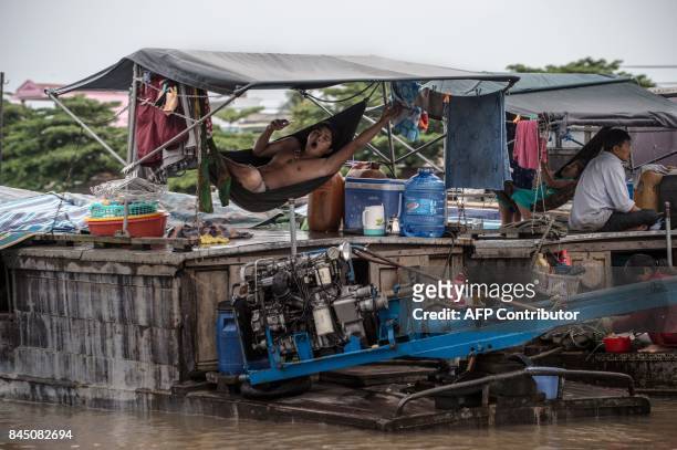 In this July 17, 2017 photograph, a resident of a house boat yawns as he swings on a hammock on the vessel in a canal off the Song Hau river at the...