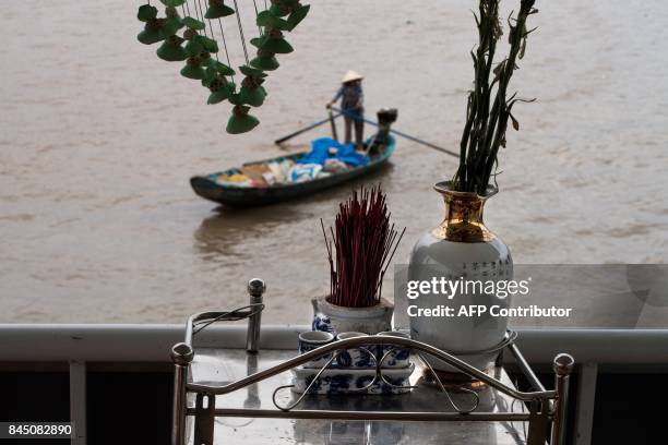 In this July 17, 2017 photograph, a small shrine is seen on the deck of a river boat catering to tourists as a river vendor paddles past in search of...