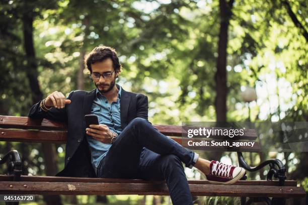 man texting in park - public park bench stock pictures, royalty-free photos & images