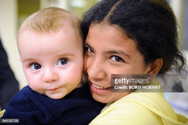 Nojoud Ali, a 11-year-old girl from Yemen poses with a baby on January 28, 2009 in Paris, on the sideline of a debate organized by the Women's rights...