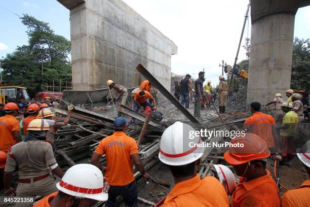 And fire fighters look near the under construction bridge collapse area as they are busy in the rescue works from the debris of collapsed bridge in...