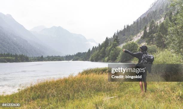 man met de hand in de buurt van het meer in de regen te wijzen - kapstaden stockfoto's en -beelden