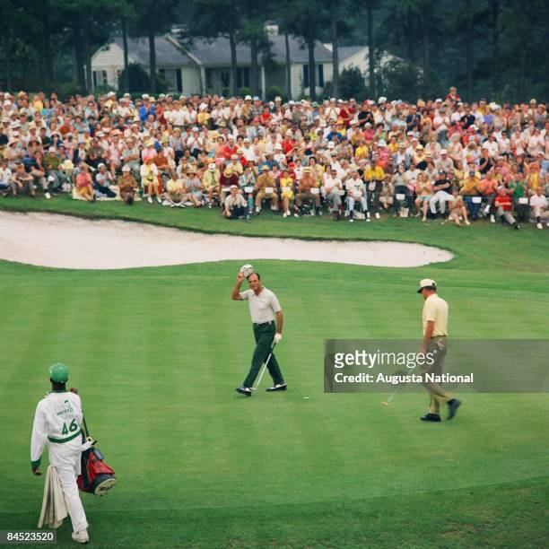Roberto de Vicenzo tips his hat to the gallery as Tommy Aaron walks to the hole during the 1968 Masters Tournament at Augusta National Golf Club on...