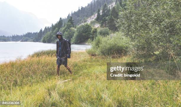 man in regenvest komt naar de camera in de regen - kapstaden stockfoto's en -beelden