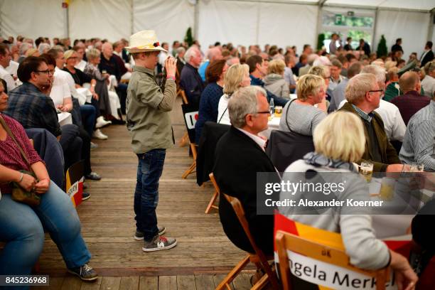 Supporters of German Chancellor and Christian Democrat Angela Merkel listen to her speech at a fest tent during an election campaign stop on...