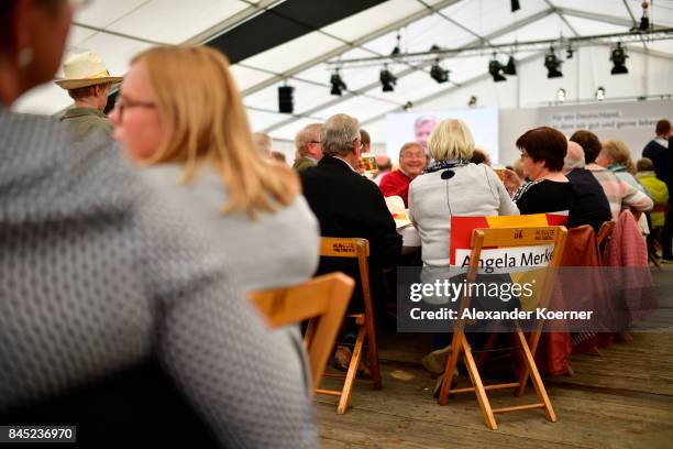 Supporters of German Chancellor and Christian Democrat Angela Merkel listen to her speech at a fest tent during an election campaign stop on...