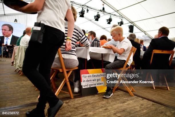 Supporters of German Chancellor and Christian Democrat Angela Merkel listen to her speech at a fest tent during an election campaign stop on...