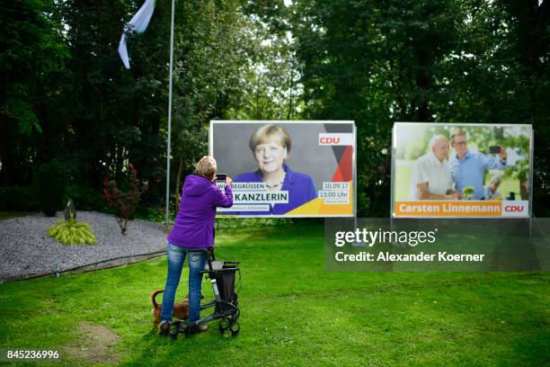 Supporter of German Chancellor and Christian Democrat Angela Merkel takes a photo of a billboard at a fest tent during an election campaign stop on...