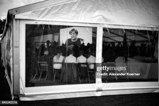 Supporters of German Chancellor and Christian Democrat Angela Merkel listen to her speech at a fest tent during an election campaign stop on...