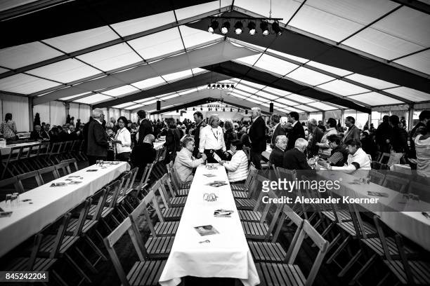 Supporters of German Chancellor and Christian Democrat Angela Merkel sit and wait prior a speech to supporters at a fest tent during an election...
