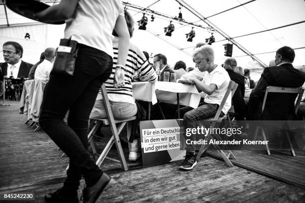 Supporters of German Chancellor and Christian Democrat Angela Merkel listen to her speech at a fest tent during an election campaign stop on...