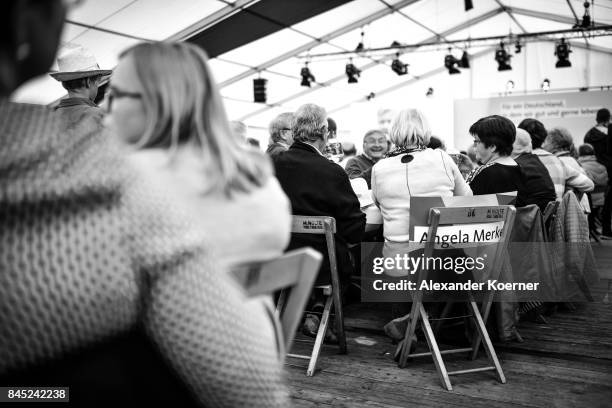 Supporters of German Chancellor and Christian Democrat Angela Merkel listen to her speech at a fest tent during an election campaign stop on...