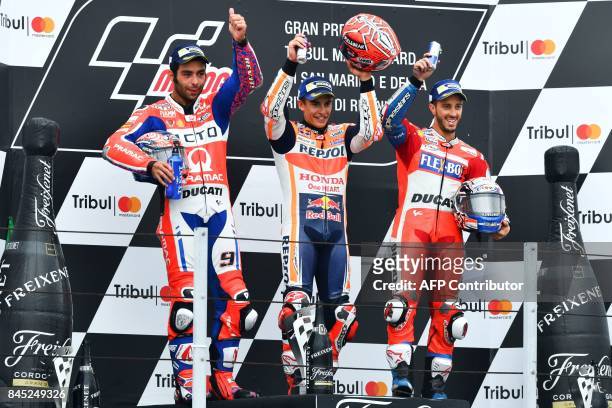 Repsol Honda Team's Spanish rider Marc Marquez celebrates winning on the podium to second-placed Ducati Team's Italian rider Danilo Petrucci and...