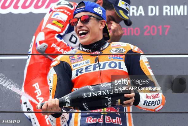 Repsol Honda Team's Spanish rider Marc Marquez sprays champagne as he celebrates on the podium after winning the San Marino Moto GP Grand Prix at the...