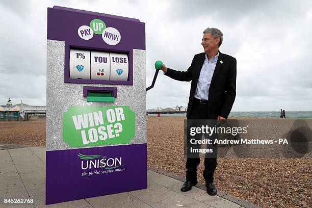 General secretary Dave Prentis pulls the lever on a mock-up slot machine on Brighton seafront as part of their âPay Up Now!â campaign,...