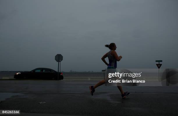 With the sky turning dark above her and the wind picking up, a jogger runs on Bayshore Boulevard along Tampa Bay ahead of Hurricane Irma on September...