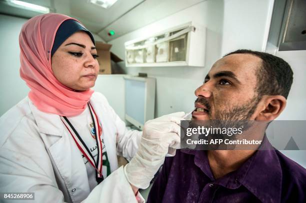 An Egyptian medical staffer takes oral samples from a labourer undergoing examination for Hepatitis C, at the construction site of Egypt's new...