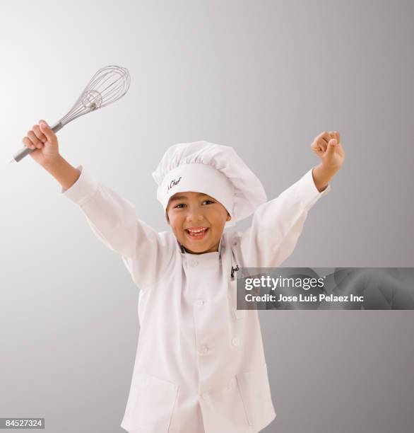 mixed race boy in chef's whites holding whisk - traditionele koksmuts stockfoto's en -beelden