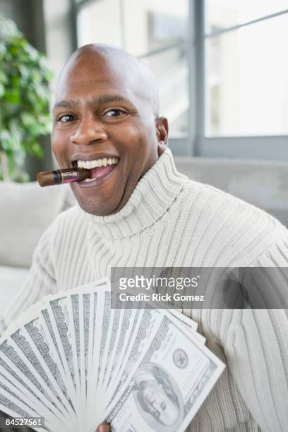 african man smoking cigar and holding 100 dollar bills - the fan of cigars stock-fotos und bilder