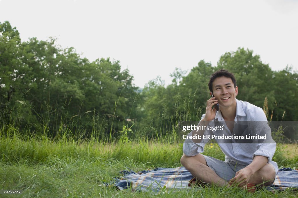 Asian man talking on cell phone in park