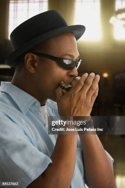african man in hat and sunglasses playing harmonica - harmonica stock-fotos und bilder