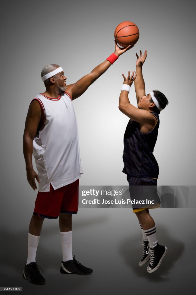Tall basketball player keeping ball from shorter player