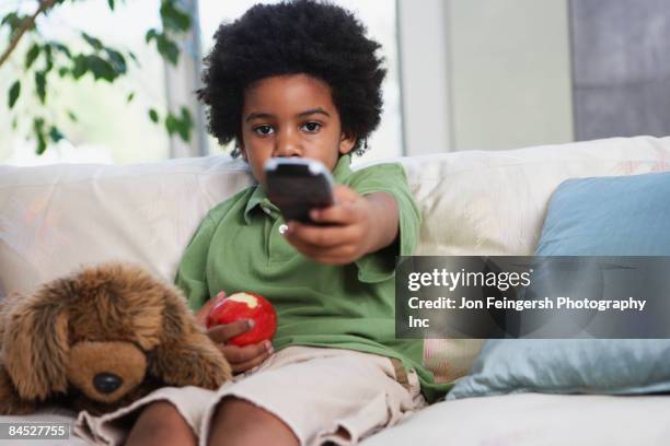 african boy eating apple and watching television - alter tv stock pictures, royalty-free photos & images