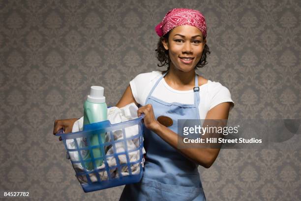 mixed race housewife carrying laundry in basket - laundry detergent stock-fotos und bilder