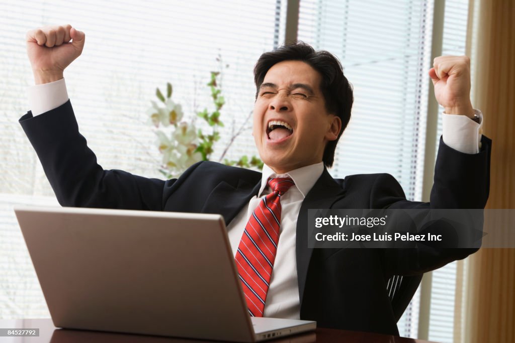 Chinese businessman with laptop cheering