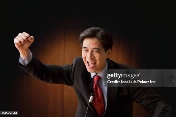 cheering chinese businessman speaking at podium - microphone debate stock pictures, royalty-free photos & images