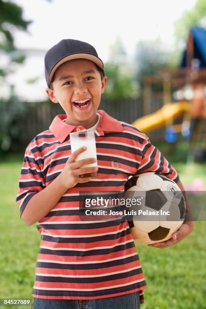 mixed race boy drinking milk and holding soccer ball - boy drinking milk stock pictures, royalty-free photos & images