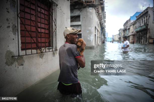 Cuban carrying his pet wades through a flooded street in Havana, on September 10, 2017. Deadly Hurricane Irma battered central Cuba on Saturday,...