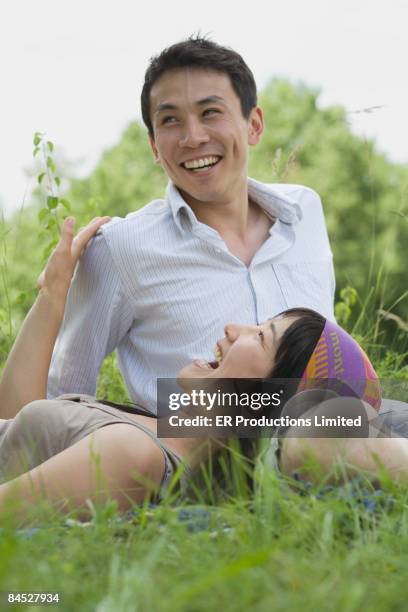 asian couple laughing in park - saia midi stock-fotos und bilder