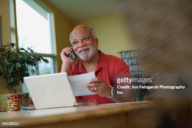 african man talking on telephone while paying bills - man holding paper stock pictures, royalty-free photos & images