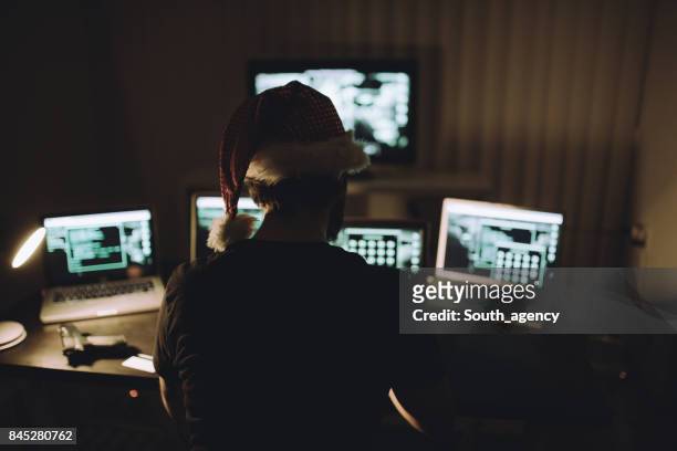 hacker wearing christmas hat - christmas thief stock pictures, royalty-free photos & images