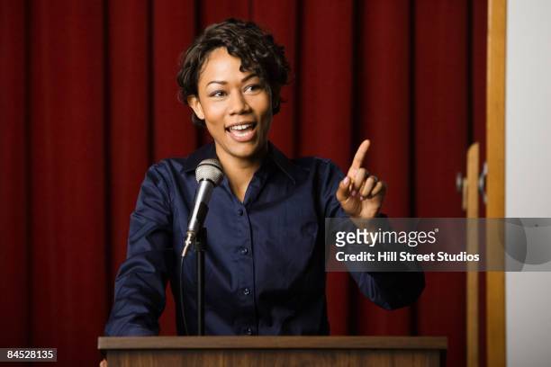 mixed race businesswoman speaking at podium - politica foto e immagini stock