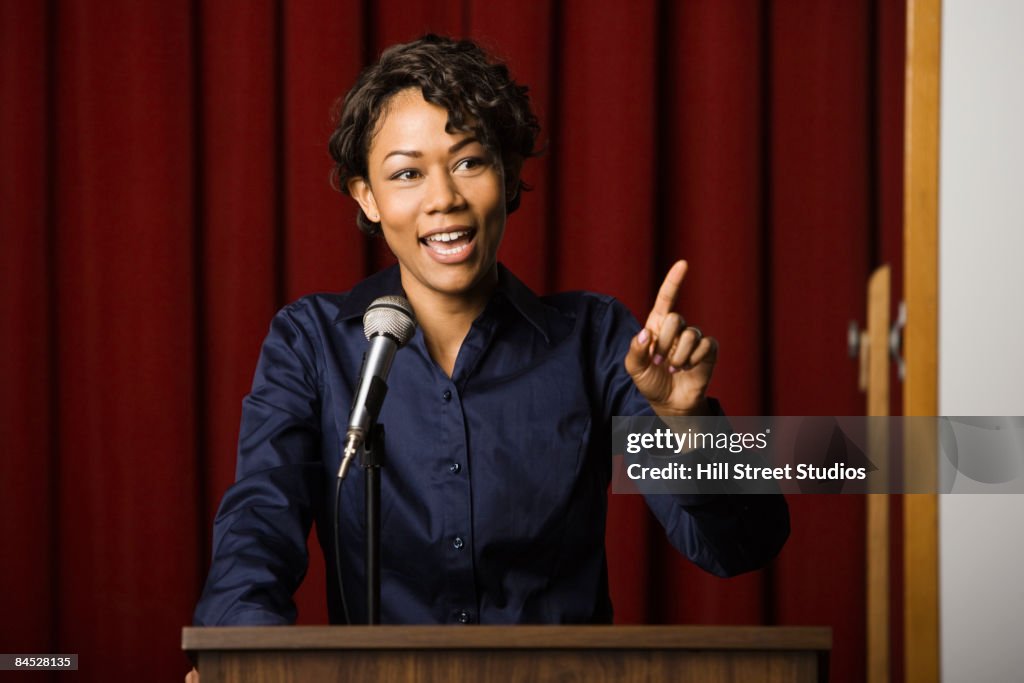Mixed race businesswoman speaking at podium