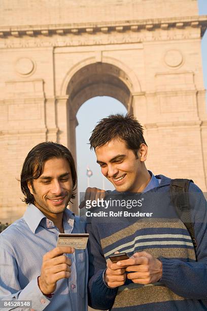 indian friends with cell phone and credit card near the india gate - india gate photos et images de collection